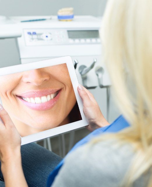 Woman looking at trial smile cosmetic dentistry plan on tablet computer