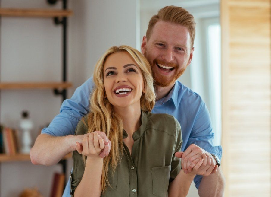 Man and woman smiling together after dental crown and fixed bridge restoration