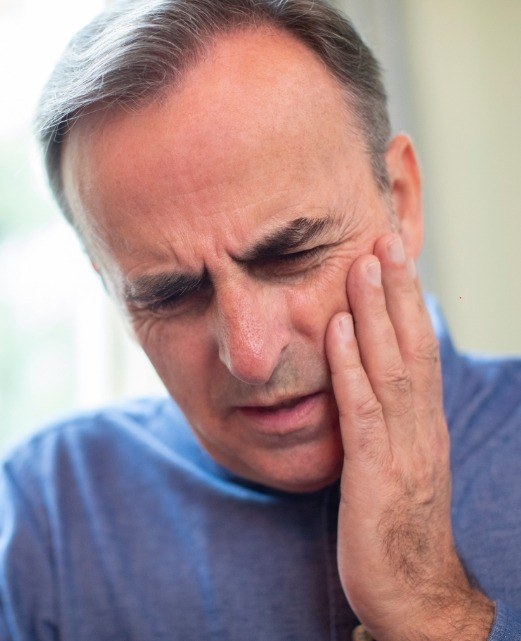 Man in pain following tooth loss holding cheek