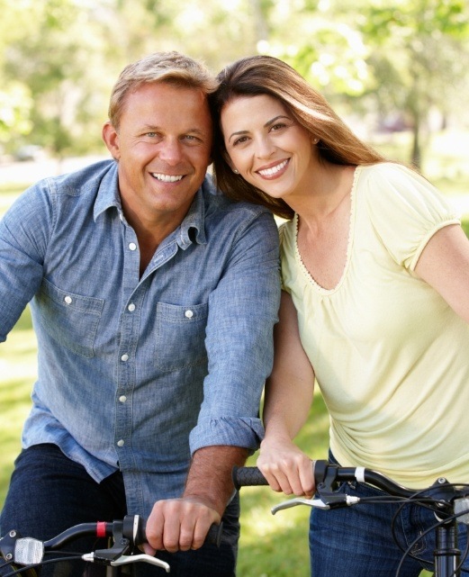 Man and woman smiling together after replacing missing teeth