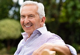 Man with dental implants in Spring Lake, NJ sitting on park bench