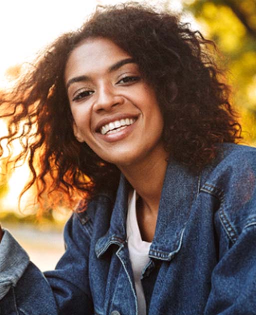 Woman smiling outside after visiting implant dentist in Spring Lake