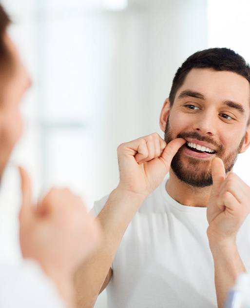 Man using floss to practice dental implant care in Spring Lake