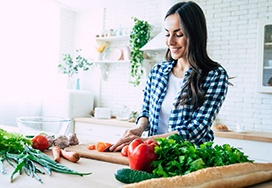 Smiling woman with dental implants in Spring Lake preparing meal