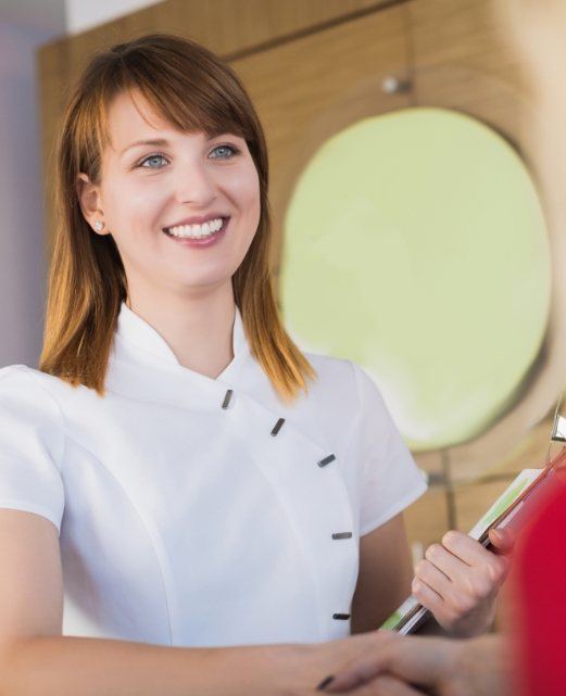 Smiling dental team member holding a clipboard