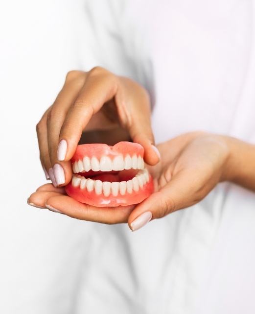 Hand holding full set of dentures