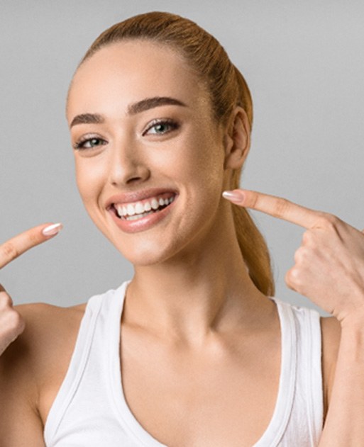 Woman pointing at her veneers in Spring Lake