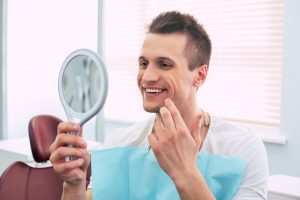 a young man smiling in the mirror at the dentist’s office