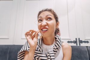 woman using a toothpick on stuck food in her teeth
