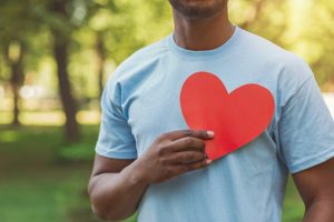 a person holding a paper heart over their chest