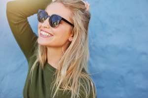 a woman in sunglasses smiling during the summertime